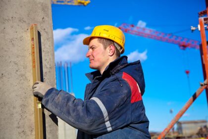 Construction worker checking vertical level of house wall