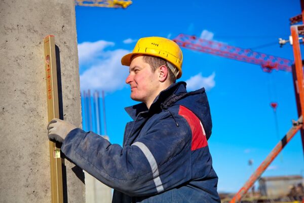 Construction worker checking vertical level of house wall