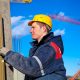 Construction worker checking vertical level of house wall