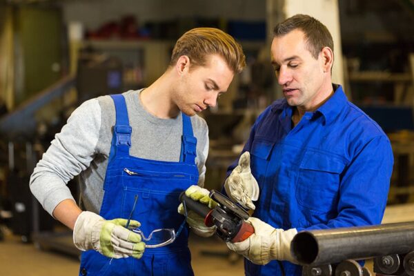instructor teaches trainee how to use an angle grinder