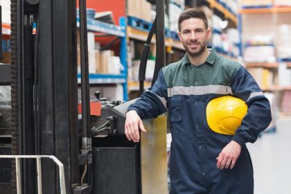 Manual worker leaning against the forklift in warehouse