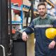 Manual worker leaning against the forklift in warehouse
