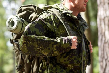 close up of young soldier with backpack in forest