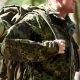 close up of young soldier with backpack in forest